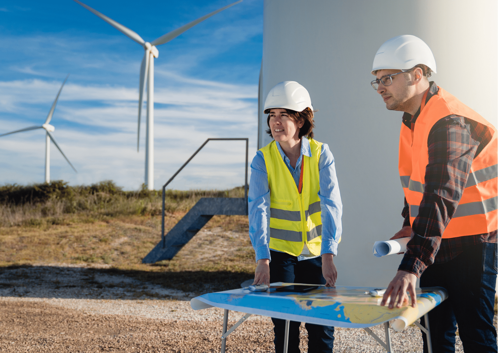 Femme et homme avec un casque de chantier avec des éoliennes en fond